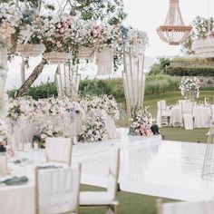 an outdoor wedding setup with flowers and chandeliers