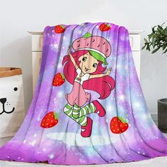 a blanket that has a cartoon character on it with strawberries in the foreground