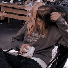 two people sitting in chairs playing video games with remote controllers on their heads and one person holding a game controller up to her ear