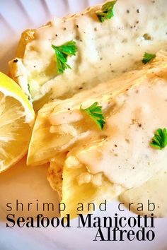 shrimp and crab seafood manicotti alfredo on a white plate with lemon wedges