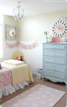 a child's bedroom decorated in pastel colors with pink and white accessories on the dresser