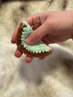 a hand holding a cookie with green icing on it's top and bottom