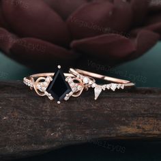 a black diamond ring sitting on top of a piece of wood next to a flower