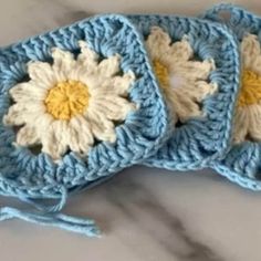 two crocheted blue and white flowers on top of each other with yellow centers