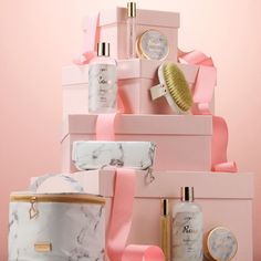 a stack of pink and white boxes with various items on top of each one, including a brush