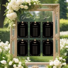 a table plan with white flowers and greenery in front of a gold framed mirror