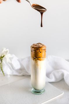 someone is spooning chocolate sauce into a jar with marshmallows in it