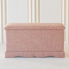 a red and white striped bench sitting on top of a floor next to a wall