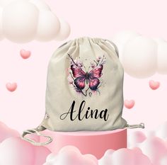 a drawsack bag with a pink butterfly on it and the name alina in black ink