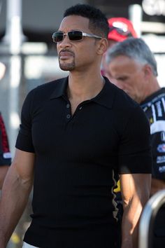 a man in black shirt and sunglasses walking