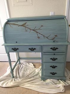 an old desk painted blue with branches on the top and bottom, sitting in front of a door