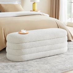 a white bed sitting on top of a wooden floor next to a beige comforter