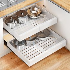 an open drawer in a kitchen with pots and pans on the bottom shelf,