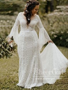 a woman in a white dress holding a bouquet and wearing a long sleeved wedding gown