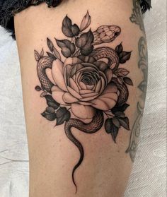 a woman's thigh with a snake and rose tattoo on it