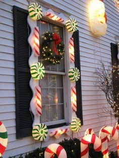 christmas decorations on the outside of a house with candy canes in front of it