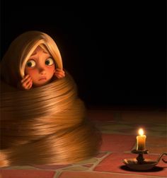 a girl with long blonde hair covering her face next to a candle on the floor