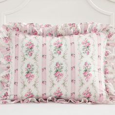 a pink and white floral pillow with ruffled edges