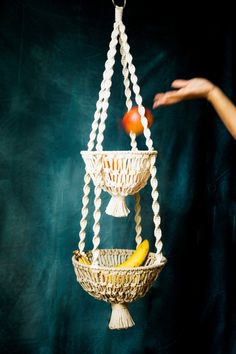 a person reaching out towards a hanging fruit basket