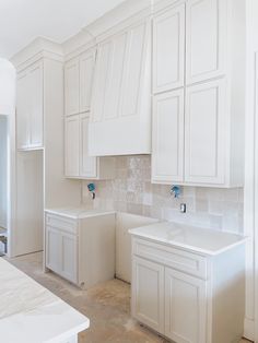 an empty kitchen with white cabinets and counter tops