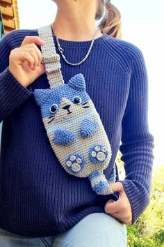 a woman is holding a crocheted cat bag