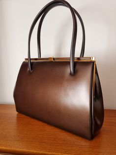 Description: Vintage Deep Brown Classic Top Handle Handbag. Elbief Frame Measurements:Width: 29cm, Height: 21cm, Bag to Strap: 16.5cm Retro Travel Bags With Gold-tone Hardware, Formal Brown Baguette Bag With Double Handle, Classic Handheld Baguette Bag With Top Carry Handle, Retro Satchel Bag With Gold-tone Hardware, Formal Brown Satchel Baguette Bag, Classic Brown Baguette Bag With Top Carry Handle, Vintage Baguette Shoulder Bag For Evening, Retro Shoulder Satchel With Gold-tone Hardware, Retro Satchel With Gold-tone Hardware