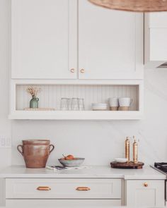 a kitchen with white cabinets and gold pulls on the cupboards, along with brass knobs