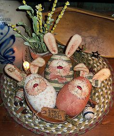 an arrangement of stuffed rabbits in a basket on a table with candles and flowers inside