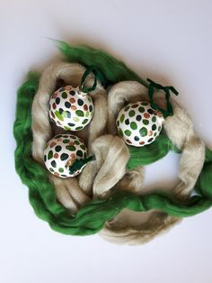 three balls of yarn sitting on top of some green fabric with white and orange dots