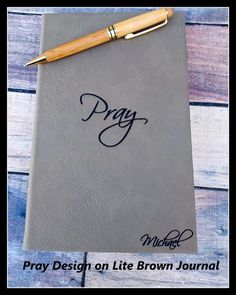 a notebook with the word pray written on it and a pen resting on top of it