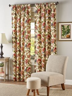 a chair and ottoman in front of a window with floral curtain panels on the windowsill