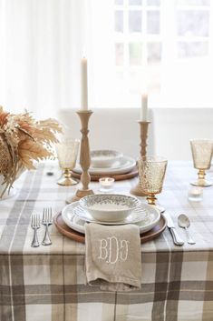 the table is set with plates, silverware and candles for an elegant fall dinner