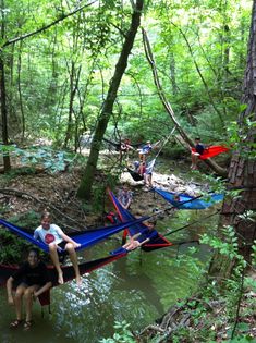 people sitting in hammocks on the edge of a stream