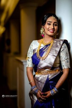 a woman in a blue and white sari standing next to a pillar with her hands on her hips