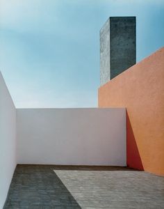 an empty room with red and orange walls next to a white wall in front of a blue sky