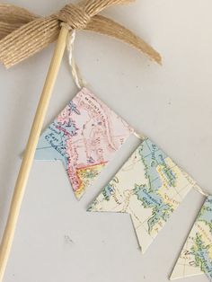 an old world map bunting banner hanging from a wooden stick on a white surface