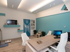 an office with blue walls and white chairs around a wooden table in front of a computer monitor