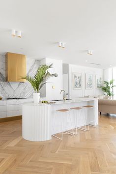 a large kitchen with marble counter tops and white cabinets, along with wooden flooring