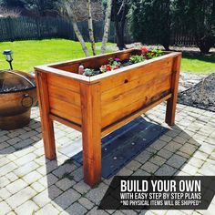 a wooden planter filled with flowers on top of a brick patio next to a fire pit