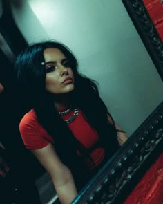 a woman with long black hair standing in front of a mirror