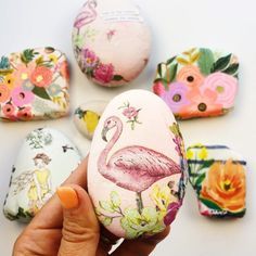 a hand holding an egg decorated with pink flamingos and other colorful flowers on it