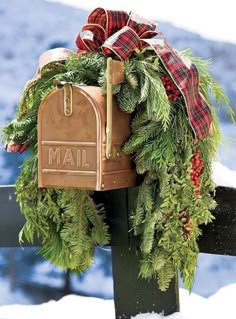 a mailbox decorated with evergreen and red plaid ribbon