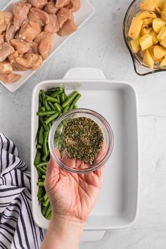 a person holding a jar filled with green beans and potatoes next to other food items