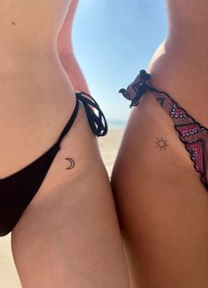 two women in bikinis with tattoos on their butts and one has a sun and moon tattoo