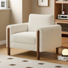 a white chair sitting in a living room next to a book shelf with books on it