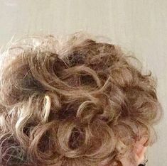 the back of a woman's head, with curly hair in an updo