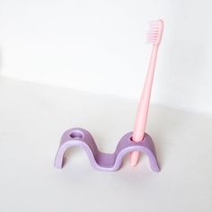 a pink and purple toothbrush holder on a white surface