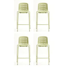 four green plastic chairs sitting next to each other on a white surface with holes in the back