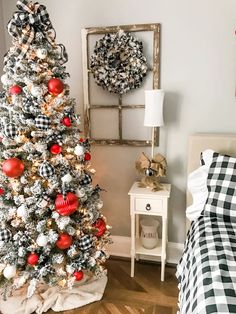 a decorated christmas tree in the corner of a bedroom with plaid bedding and black and white decor