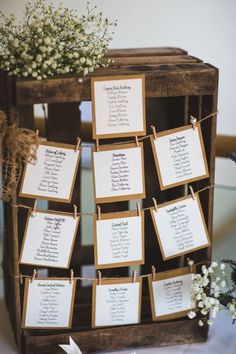 a wooden box with seating cards attached to the sides and flowers in vases next to it